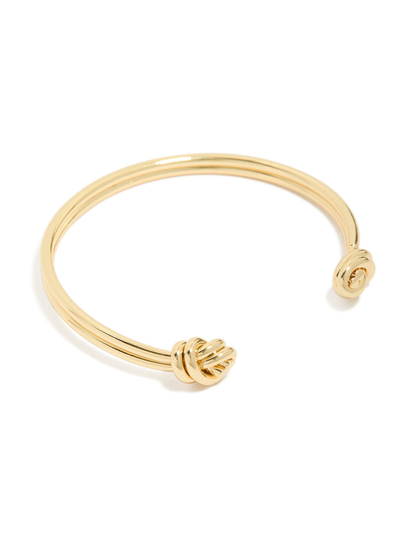 Showcasing a gold plated double knotted centre wrist cuff with statement styling front view