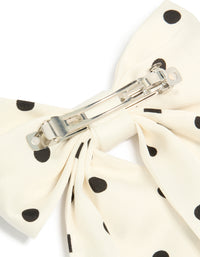 Featuring a white and black polka dot fabric bow hair clip detail view - link has visual effect only
