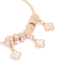 Showcasing rose gold plated triple flower charms with beads in a toggle bracelet close up view - link has visual effect only