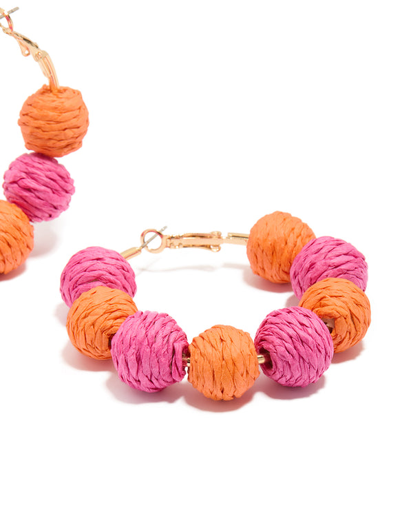 Designed with paper balls in hot pink, coral and gold, these statement hoop earrings offer post detail view