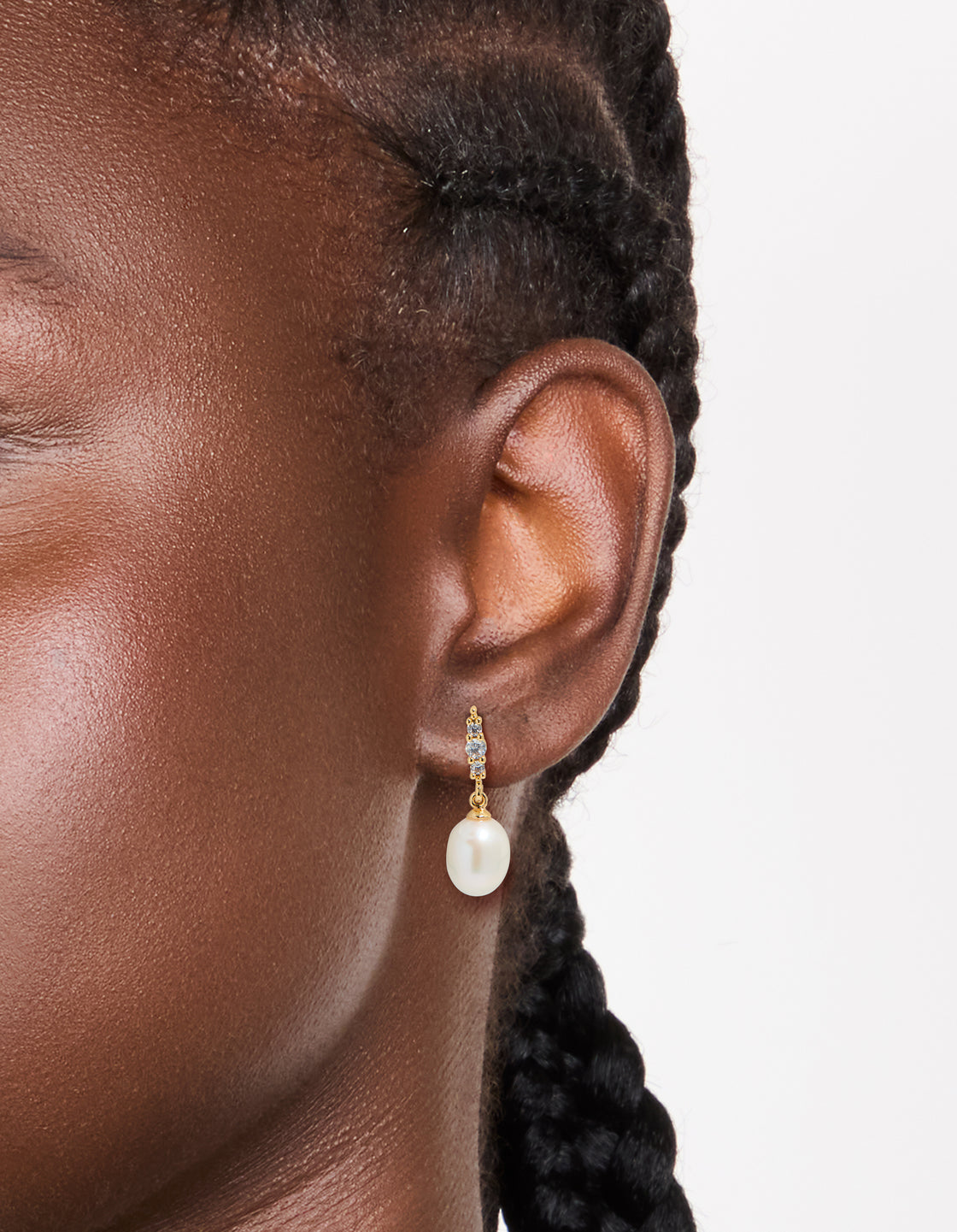 Crafted from gold plated cubic zirconia and freshwater pearl drop earrings with statement styling on ear view