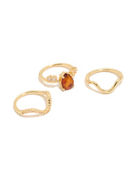 Showcasing a gold plated red cubic zirconia teardrop and wavy rings 3-pack with crystal accents in a statement style front view - link has visual effect only