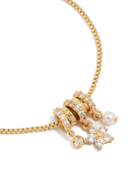 Featuring a gold plated bracelet with cubic zirconia flower and pearl rondell charm accents in a toggle design close up view - link has visual effect only