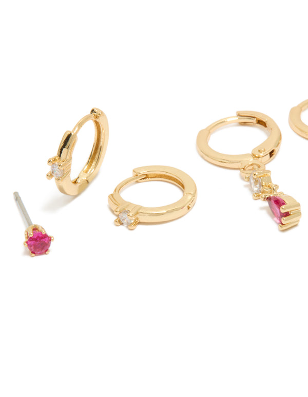 Showcasing dainty gold plated studs and huggie earrings 3-pack with dark pink cubic zirconia and crystal embellishments close up view