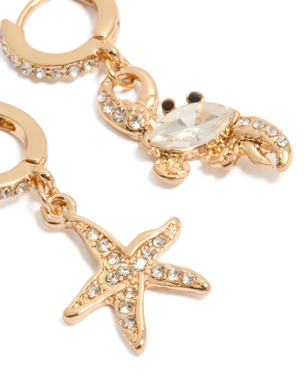 Featuring gold mismatched ocean huggie earrings with crystal embellishments close up view
