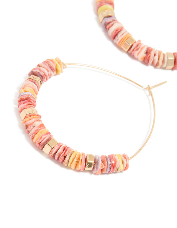 Featuring large hoop earrings with beaded genuine pink shells and statement style in gold close up view