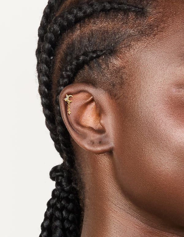 Displaying celestial charm stud earrings with moon and star design crafted from surgical steel featuring cubic zirconia and flat back closure in gold on ear view