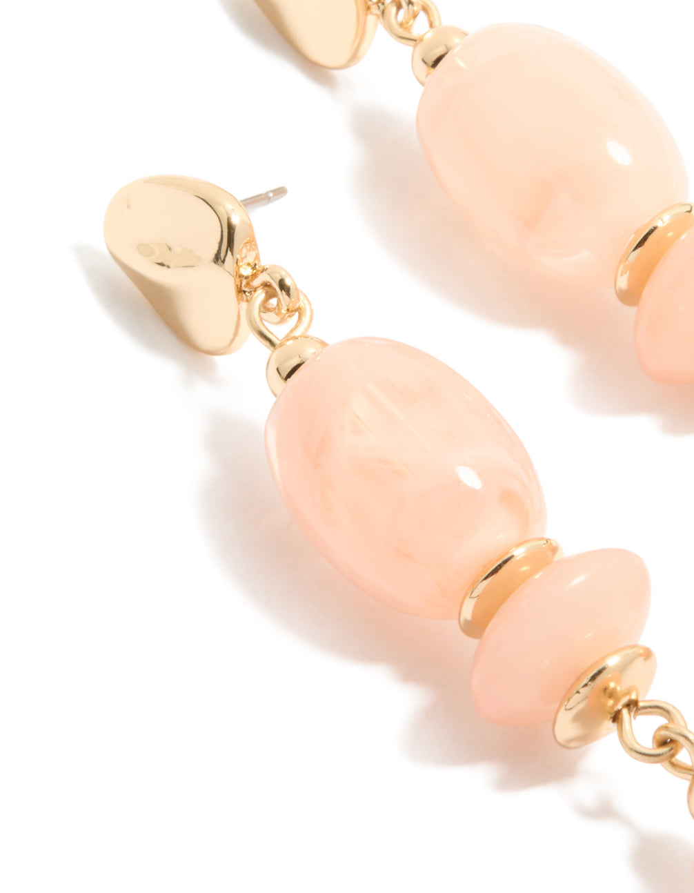 Highlighting statement drop earrings with oval beige beads and gold accents close up view