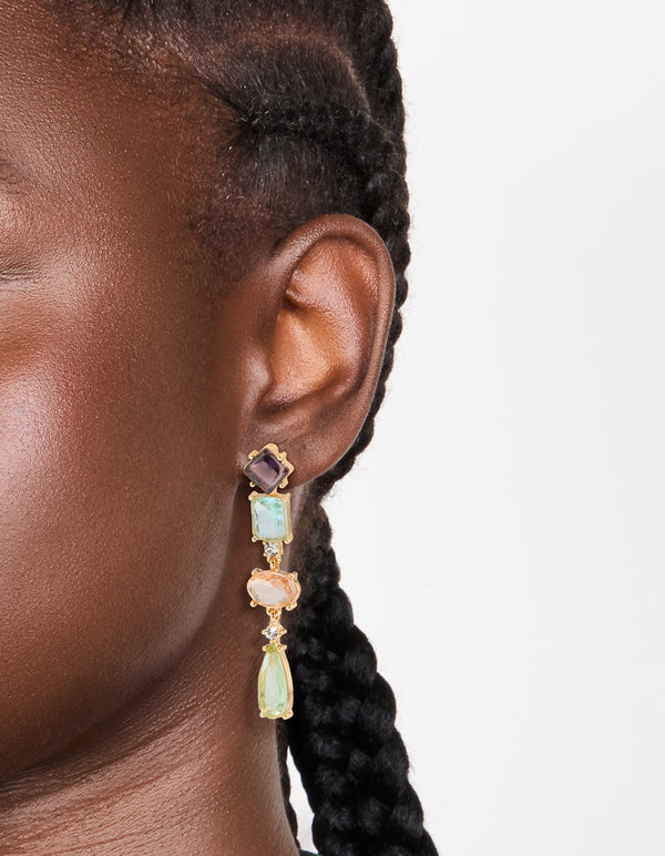 Crafted from gold, these irregular shaped purple and blue diamantes drop earrings in statement style on ear view