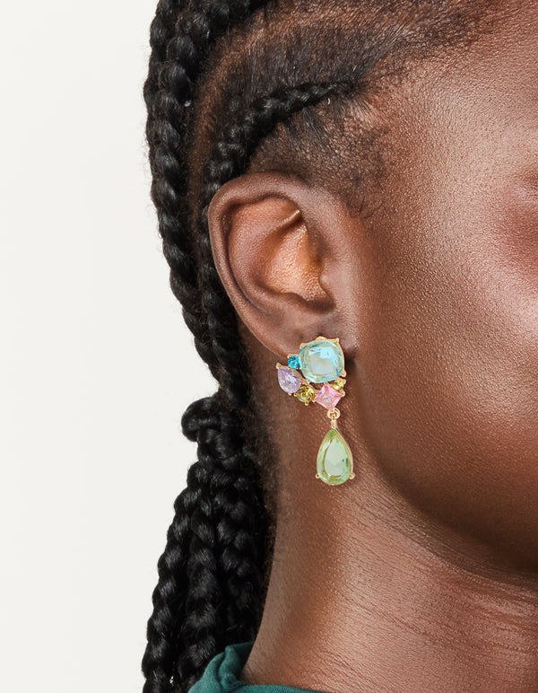 Featuring statement drop earrings with gold finish and multicolored diamante cluster in aquamarine, pale green, and pink tones on ear view