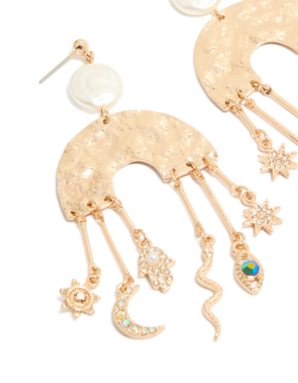 Featuring brushed gold rainbow and celestial charm drop earrings in a statement style, featuring moon, pearl, star, sun, hamsa hand, and snake charms close up view