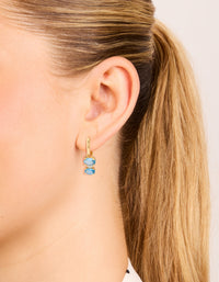 Displaying gold plated light blue cubic zirconia circles huggie earrings on ear view - link has visual effect only