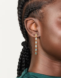 Showcasing gold plated long cubic zirconia drop earrings with aqua accents on ear view - link has visual effect only