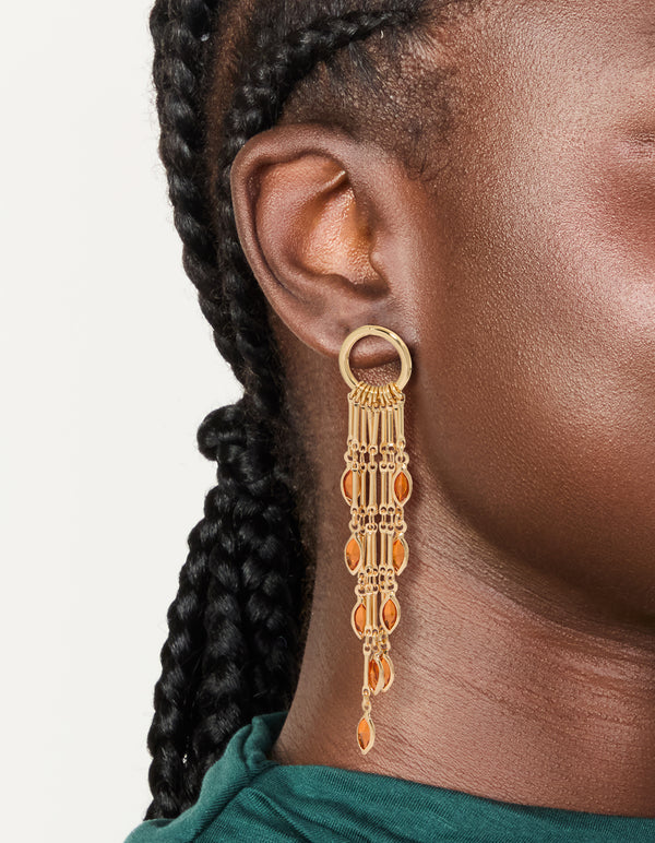 Crafted from statement style gold ring with long amber diamante chain drop earrings featuring tassel, charm orange accents on ear view