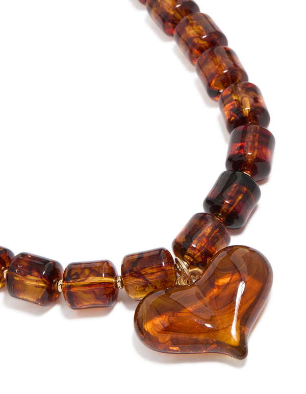 Featuring a brown square bead and heart necklace with statement in gold tones close up view